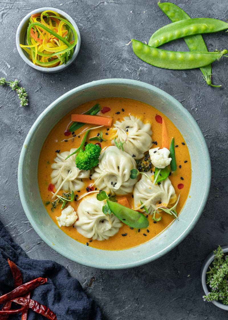 Steamed dumplings with broccoli and snow peas served in a bowl of golden curry at The Garud Forest, Tadoba