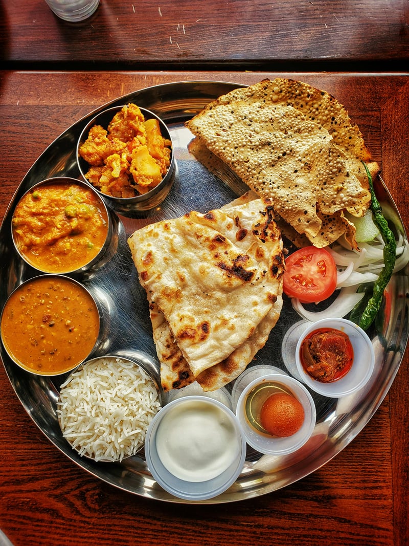 An Indian thali of curries, breads, papad, and accompaniments served on a steel platter at The Garud Forest, Tadoba