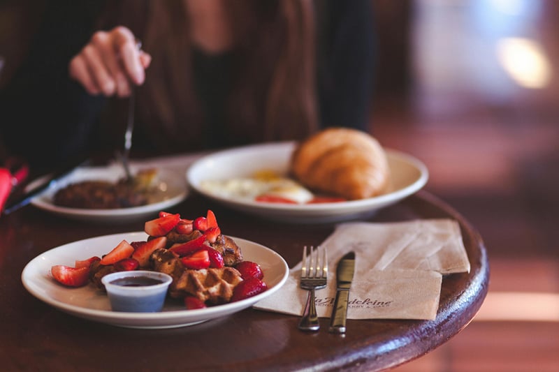 A plated breakfast of fruit, eggs, and a croissant served at a table at The Garud Forest, Tadoba