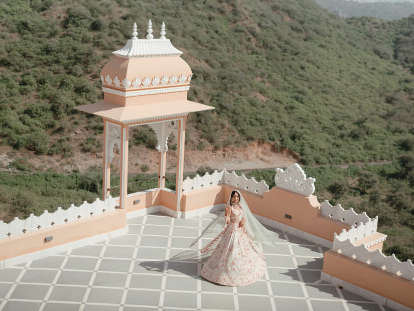 The newly wed couple dancing on a terrace of Fateh Vilas, Udaipur surrounded by green hills.