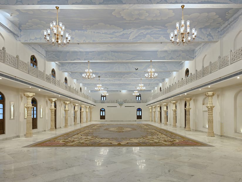 The illuminated banquet hall featuring white and cream decor with numerous chandeliers at Fateh Vilas, a wedding resort in Udaipur