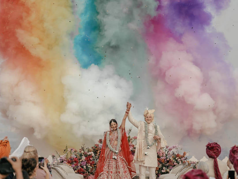 A newly wedded couple celebrating their wedding with colours flying around.
