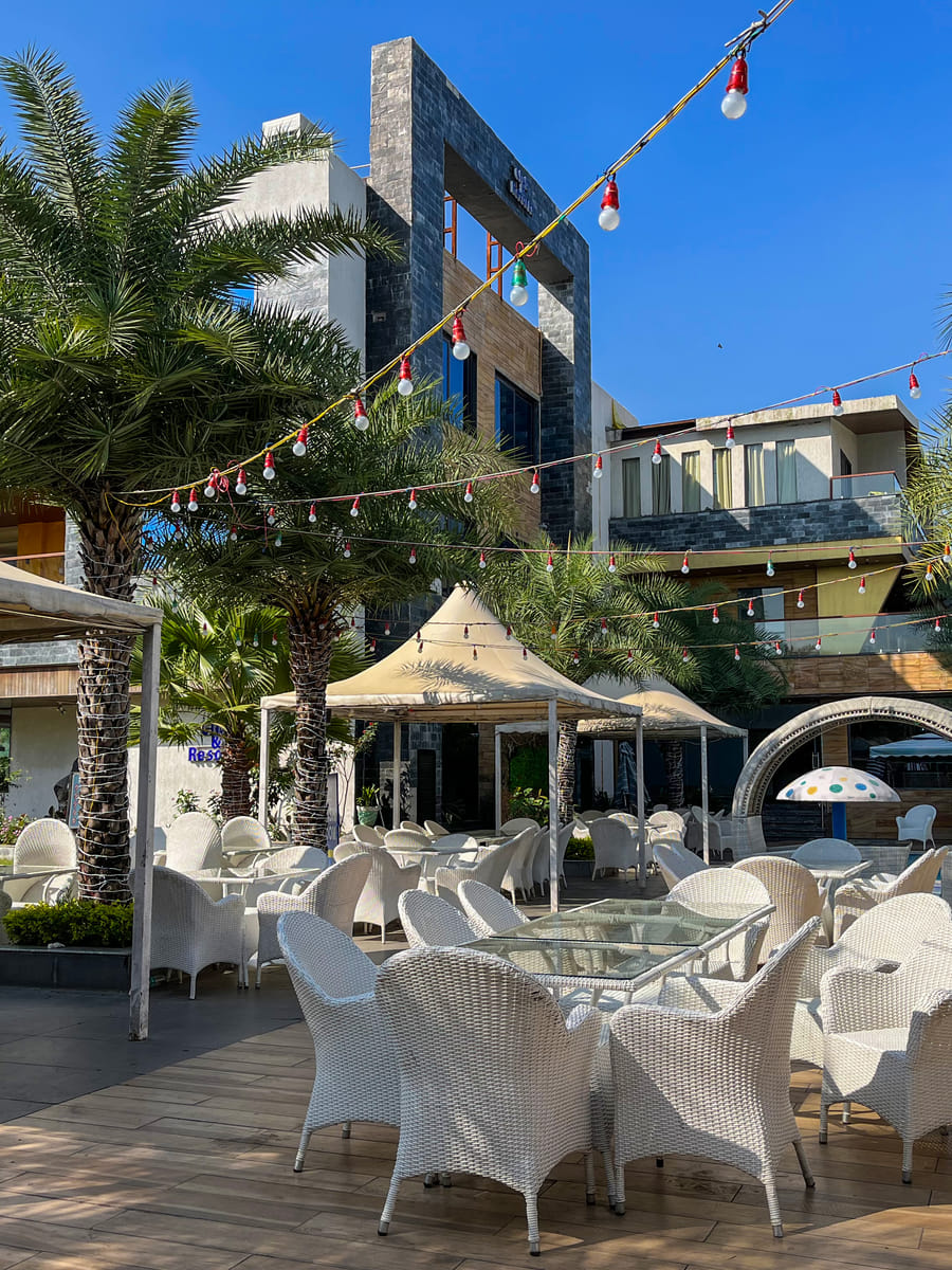 Poolside tables and wicker chairs beneath the festoon lights