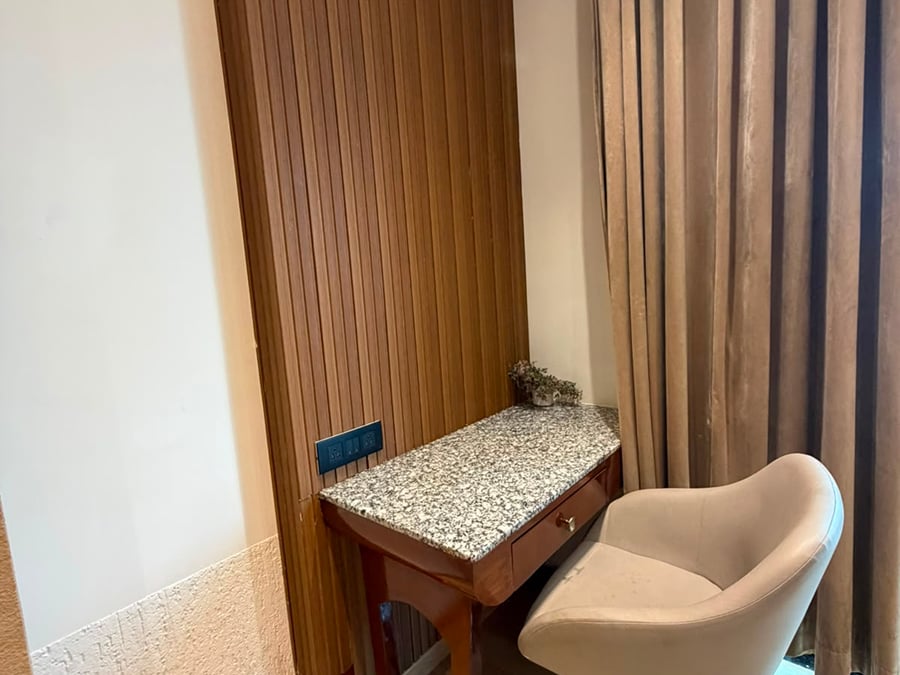 Writing desk with a granite top and a cushioned chair beside wood-panelled walls and curtains