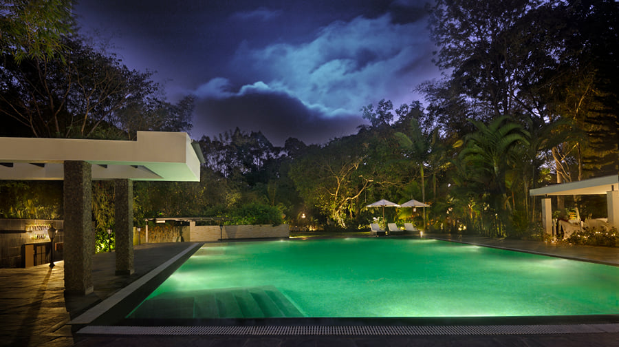 Outdoor pool at night at Amanvana Spa Resort, Kushalnagar