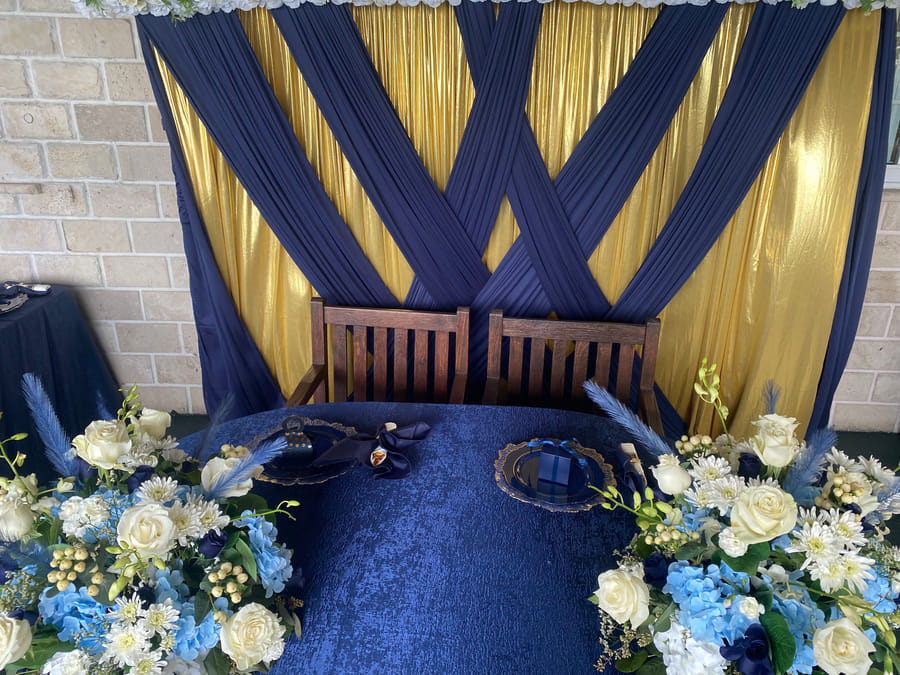 A sweetheart table set against navy and gold draping at A Stone's Throw Away