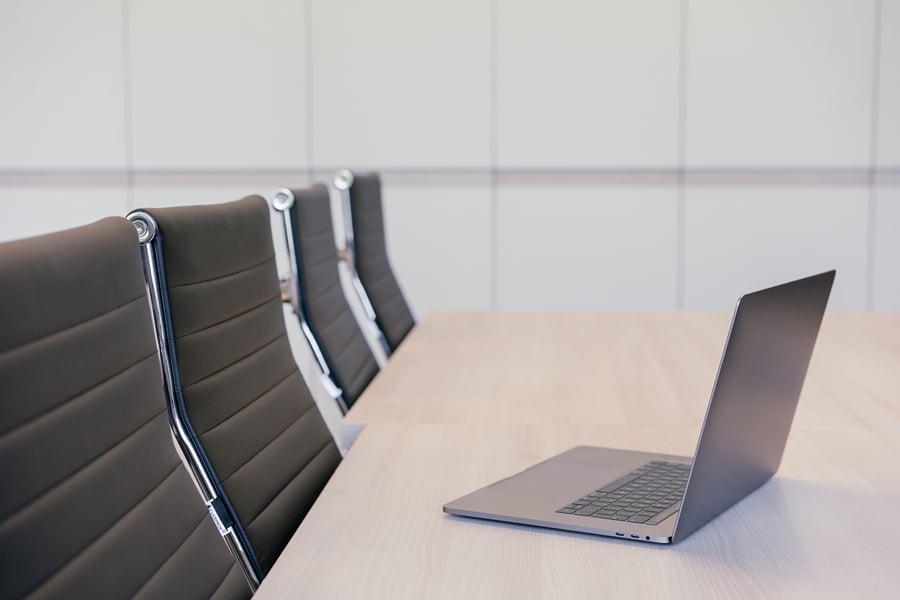 Boardroom, a long wooden meeting table with leather chairs and an open laptop