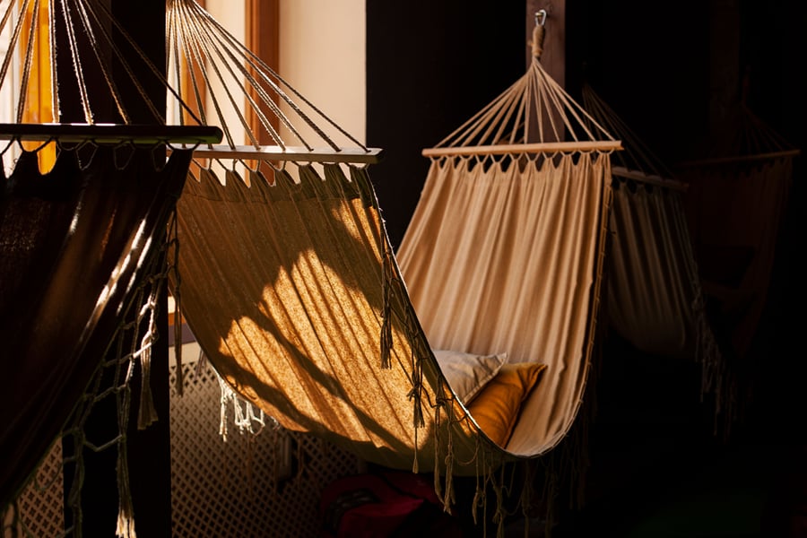 Fabric hammocks hanging in warm evening light on a shaded veranda