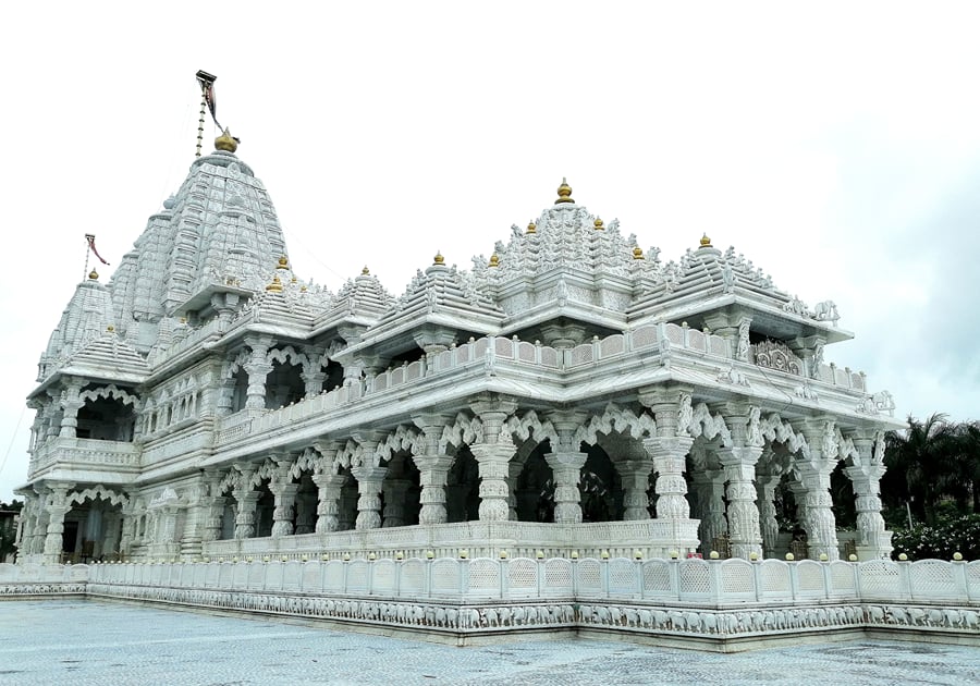 White marble temple with carved spires and pillared arcades under an overcast sky