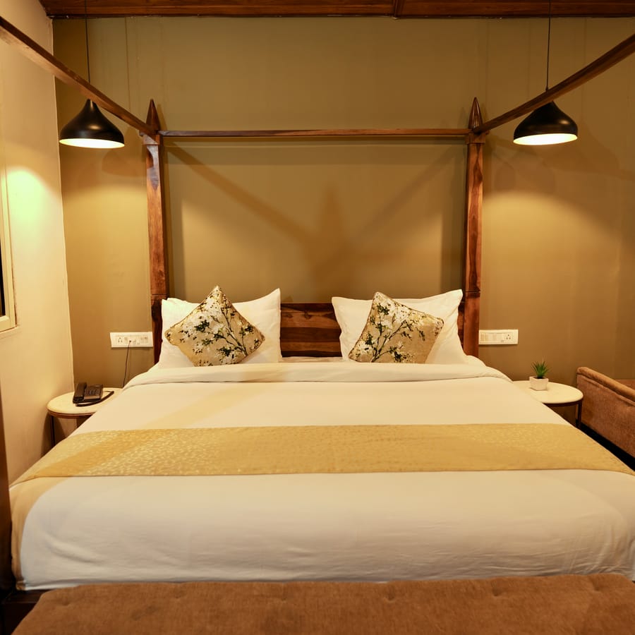 Luxurious Cottage king bed at Nazaara Nature Retreat, dressed in crisp white linen, plump pillows, and warm bedside lighting
