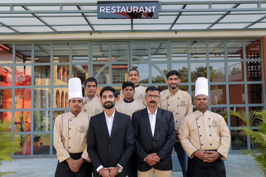 The team at Nazaara Fine Dine restaurant, Nazaara Hills Retreat, Udaipur, standing together in the dining hall.