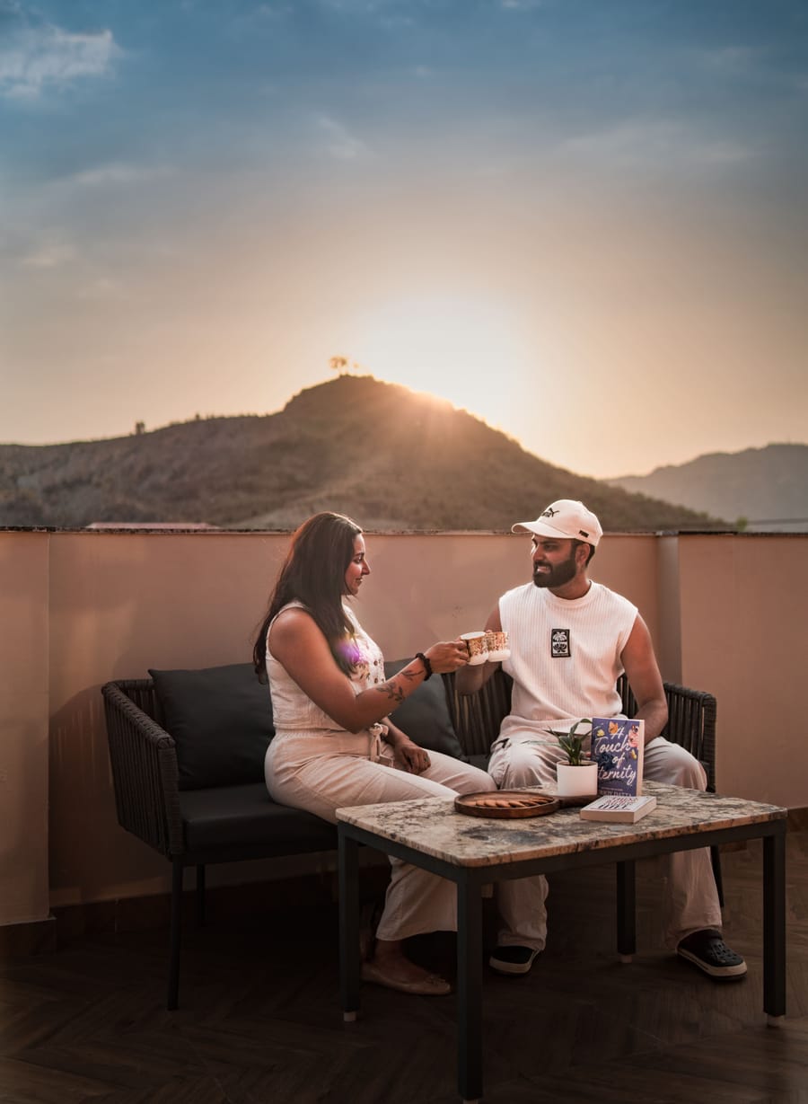A couple relaxing on the private terrace of the Nazaara Royal Suite at Nazaara Hills Retreat, Udaipur, at sunset