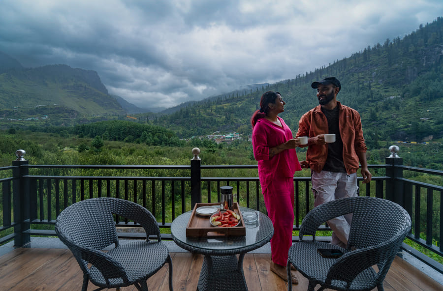Couple on the Premium Room balcony with mountain view at Nazaara Luxe Retreat, Manali