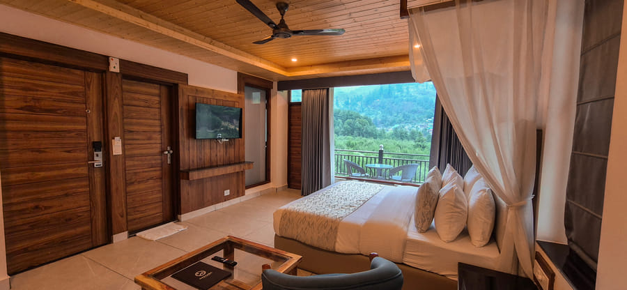 King bed viewed from the entrance doors of the Premium Room at Nazaara Luxe Retreat, Manali