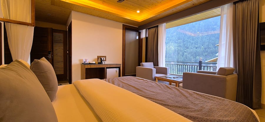 King bed beside a wooden console holding the tea and coffee maker in the Superior Room at Nazaara Luxe Retreat, Manali