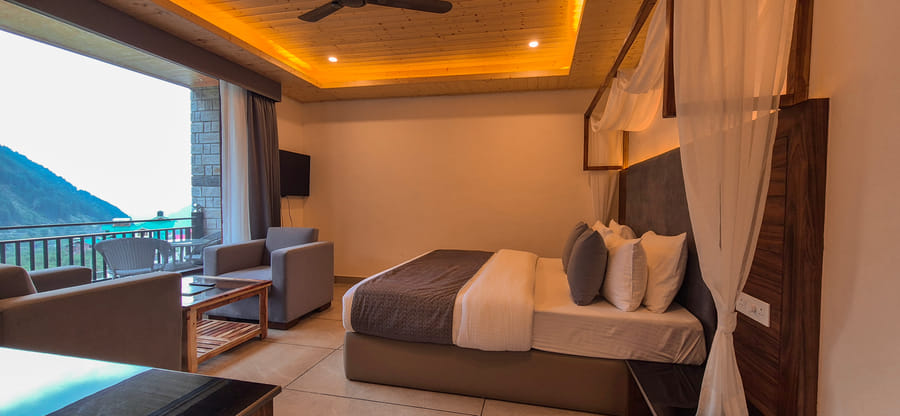 Superior Room at Nazaara Luxe Retreat, a neatly dressed bed facing a television console beside the private balcony door