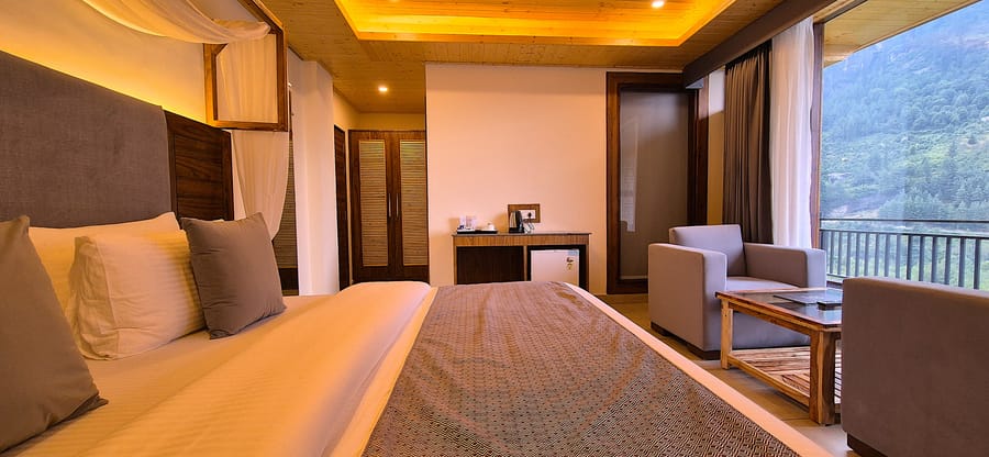 King bed, wardrobe and a pair of armchairs arranged in the Superior Room at Nazaara Luxe Retreat, Manali