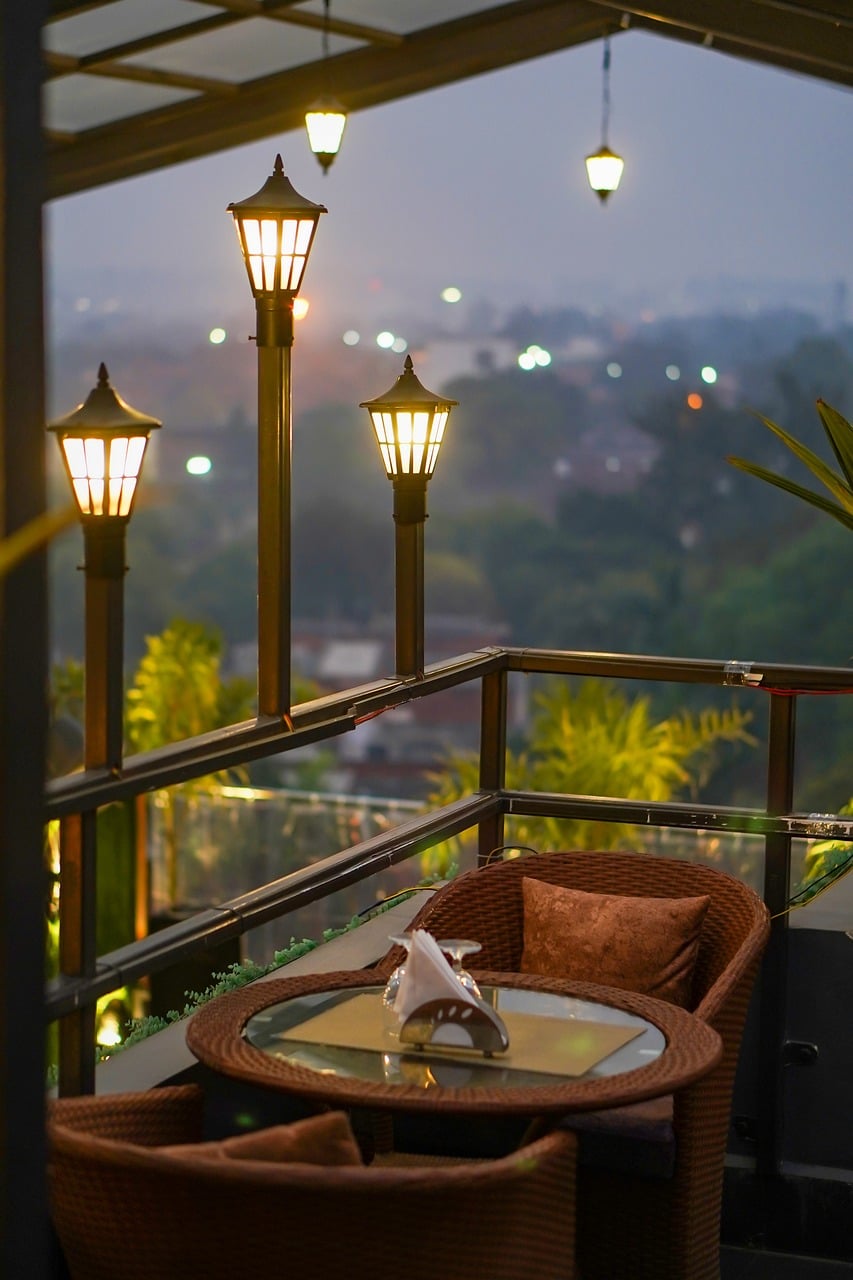 An open terrace with lanterns lit at dusk, looking out over the treeline at The Garud Forest, Tadoba