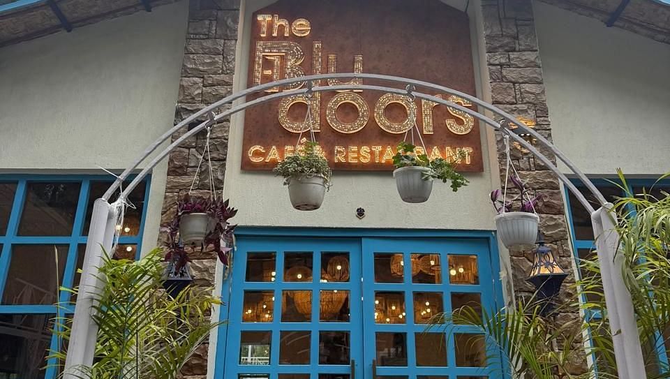 The entrance to 'The Blu Doors Cafe and Restaurant' with blue doors and illuminated signage.