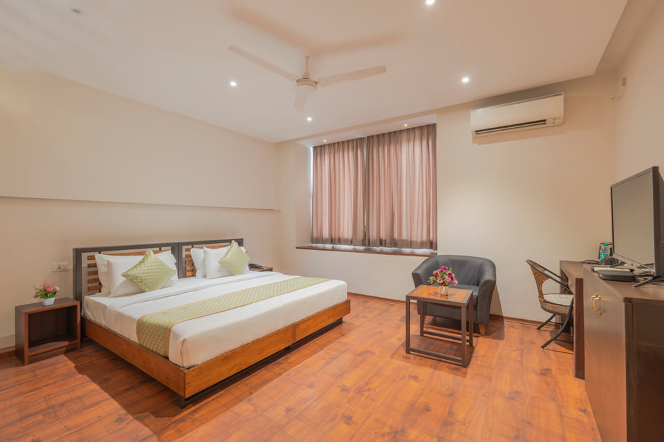 Hotel room with a queen bed, armchair and work desk