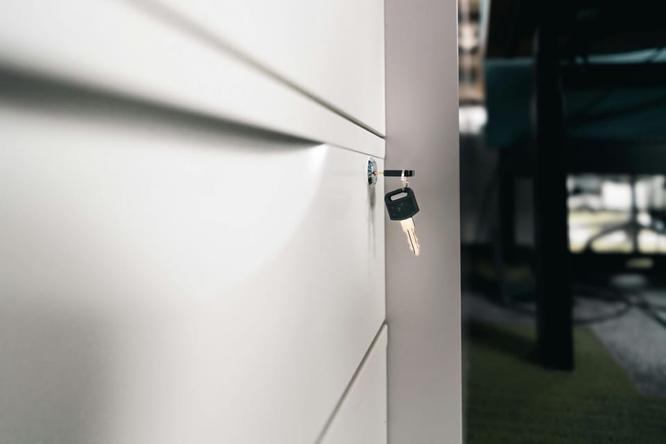 A close-up of a key inserted into the lock of a white metal locker cabinet door.