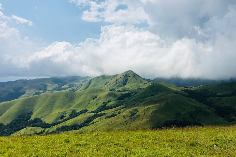 Grassy green peak with clouds rolling over the hills near Sakleshpura