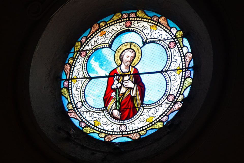 Round stained-glass window of a haloed saint in red robes at Shettihalli Rosary Church