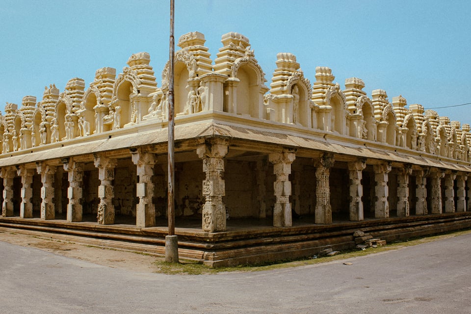 Cream temple cloister with ornate towers and pillared corridors at Shravanabelagola