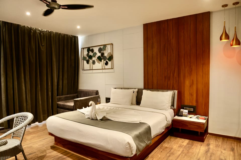 Premier room with a double bed dressed in white linen, walnut wall panelling and olive velvet curtains