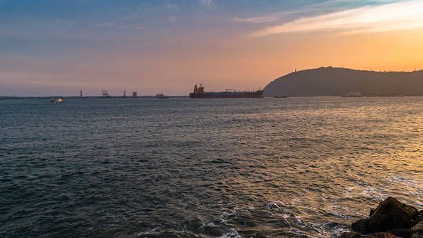 A serene ocean view with the sun setting on the horizon, casting golden hues over the water