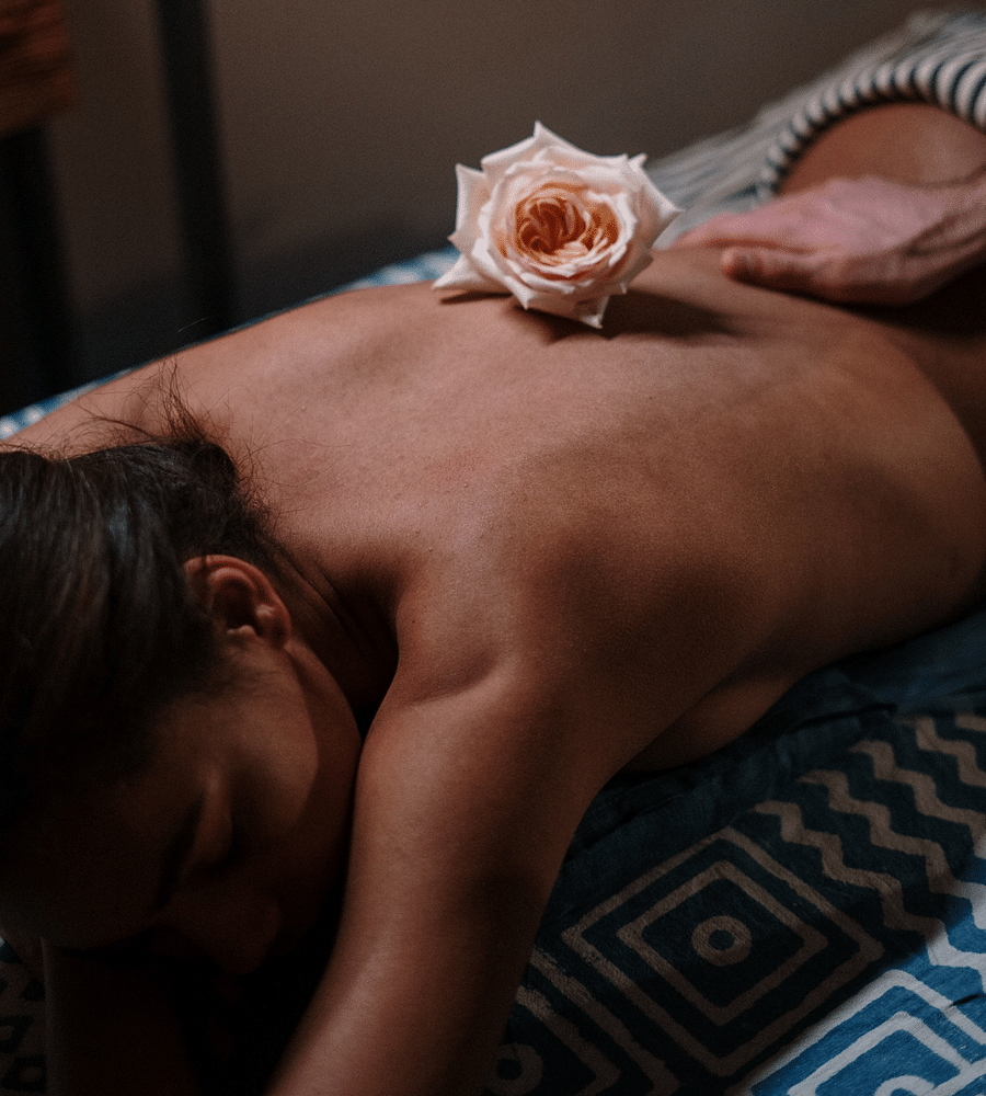 Person receiving a relaxing back massage in a spa setting, with a flower placed on their back to enhance the calming ambiance