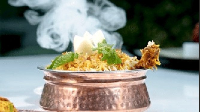 A steaming dish in a copper pot, with smoke rising and a blurred background at Cenneys Gateway - Pride of Salem.