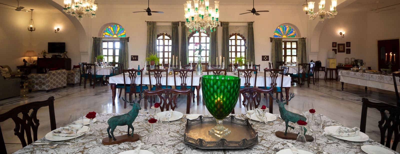 image showcaing the Indoor dining arrangement at Dev Shree, Deogarh with elegant chandeliers hanging from the top