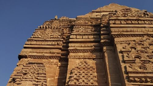 A tall stone facade of a temple within Gwalior Fort, showcasing intricate carvings and detailed architecture.