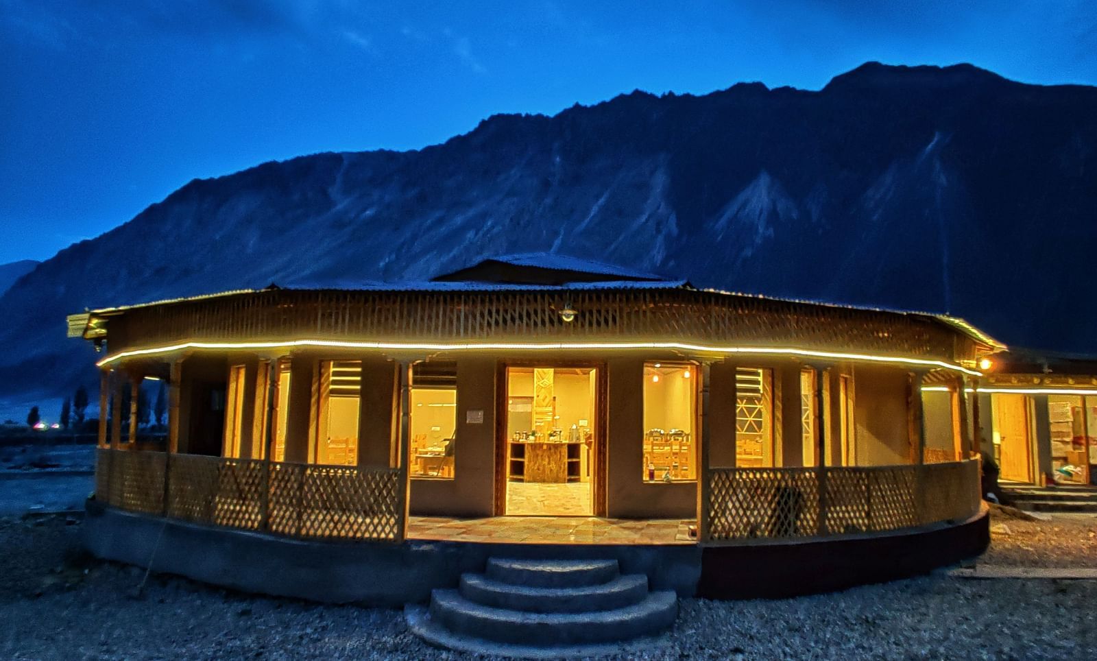 Exterior of the restaurant at White Sands Resort, Ladakh with warm lighting illuminating the structure against a dark, mountainous backdrop.
