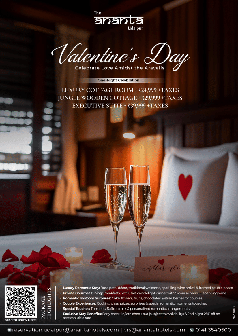 A promotional banner showcasing a Valentine’s Day romantic room setup with rose petals on the bed, a heart shaped towel arrangement, champagne glasses, a cake, and warm ambient lighting creating an intimate celebration atmosphere at The Ananta, Udaipur.