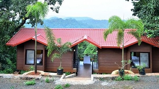 Riverview Luxury Cabin Exterior - Twin red-roofed wooden cabins in a forest setting with a mountain backdrop.