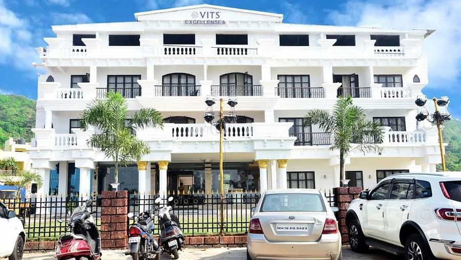 facade image of VITS ExcellenSea Dapoli with cars and bikes parked outside the fence - VITS Hotels & Resorts