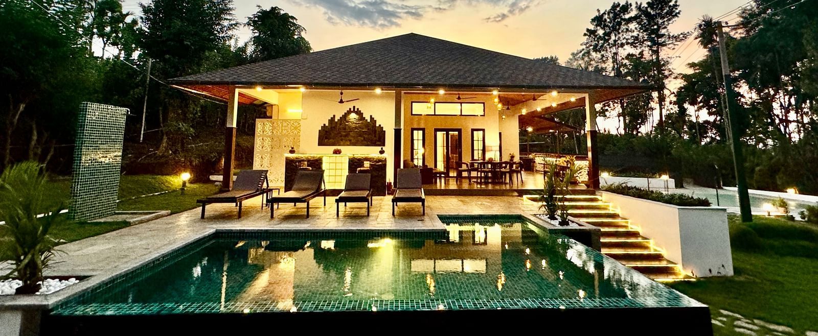 Elegant villa with a private pool reflecting the twilight sky and surrounding trees - BluSalzz Collection - Tranquil Resort, Wayanad