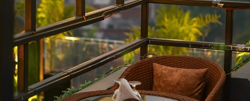 Two chairs facing each other on a terrace with warm lights besides it on a late evening.