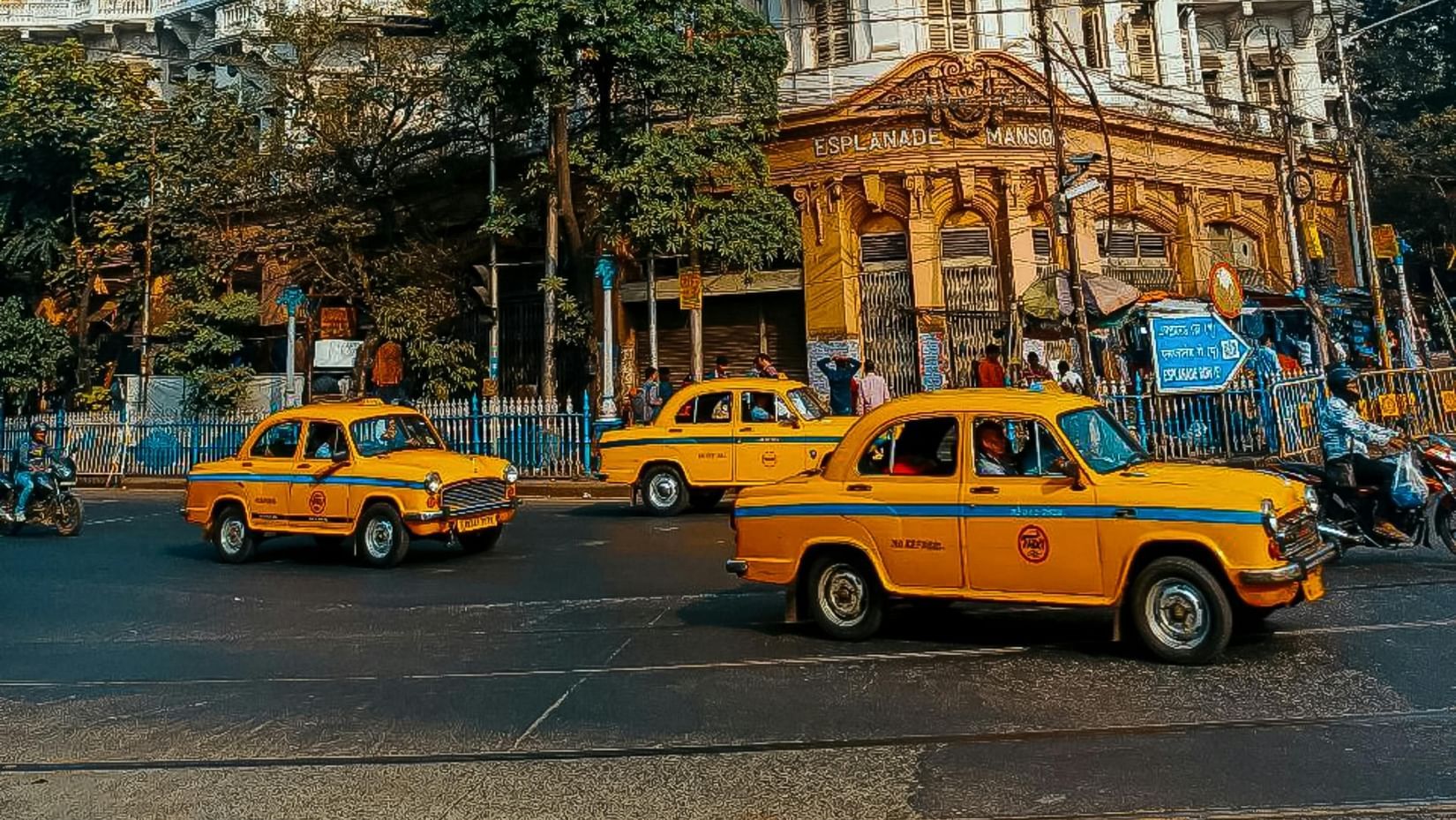 An image of the streets of Kolkata with yellow taxis and a building in the background