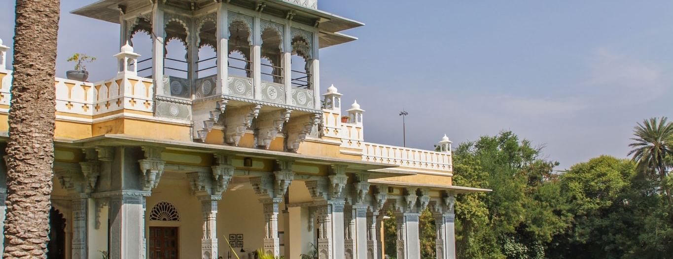 facade image of Dev Shree, deogarh featuring a vast levelled green lawn in the foreground during the day