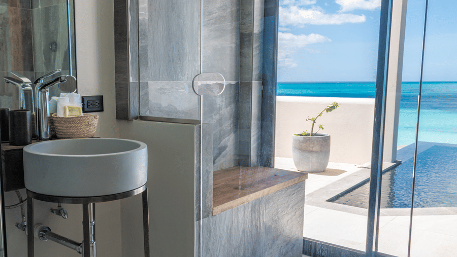A bathroom at Tamarind Hills Resort and Villas, Antigua, with a sink, glass shower, and oceanfront views by the pool.