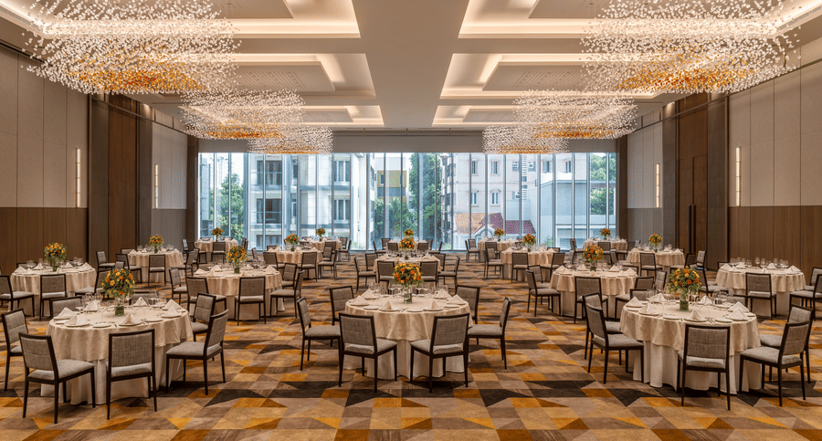 The spacious Ballroom 1 set with round banquet tables, modern chandelier lighting, and large windows at The Residency Towers Chennai.