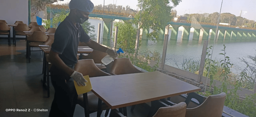 a staff member cleaning the table inside the restaurant at one of the hotels - VITS Hotels & Resorts