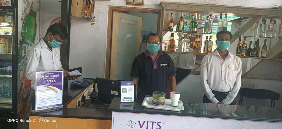 people behind a counter with vits hotels logo on the counter - VITS Hotels & Resorts