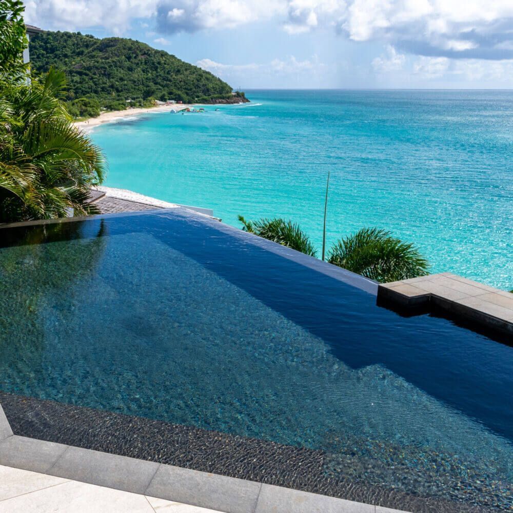 Infinity edge pool of the luxe villa in Antigua seaming into the water expanse.