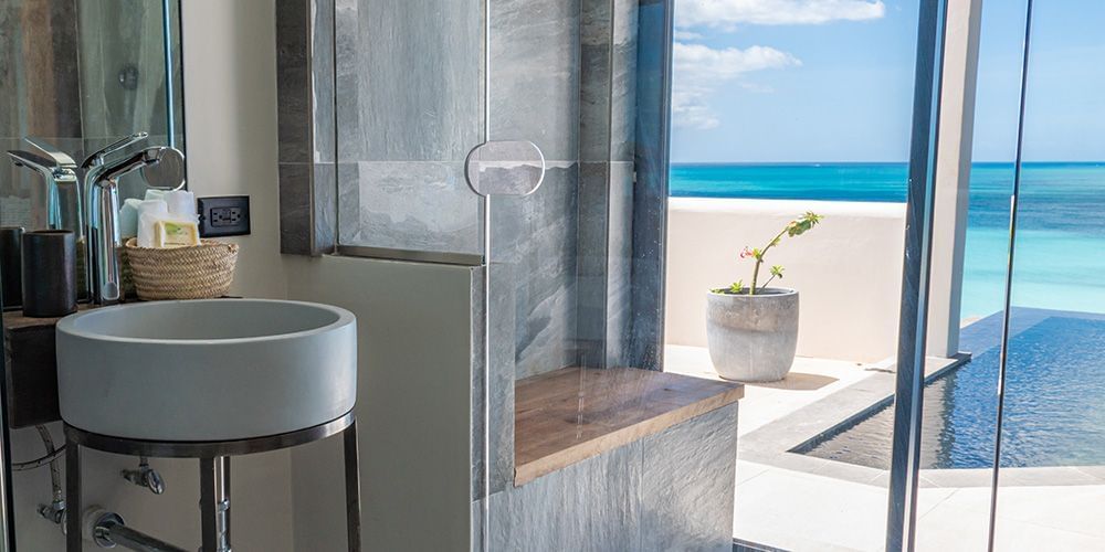 A bathroom at Tamarind Hills Resort and Villas, Antigua, with a sink, glass shower, and oceanfront views by the pool.