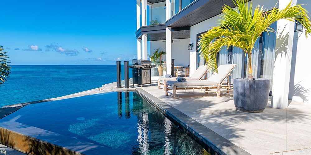 A pool next to a white villa at Tamarind Hills Resort and Villas - Antigua.