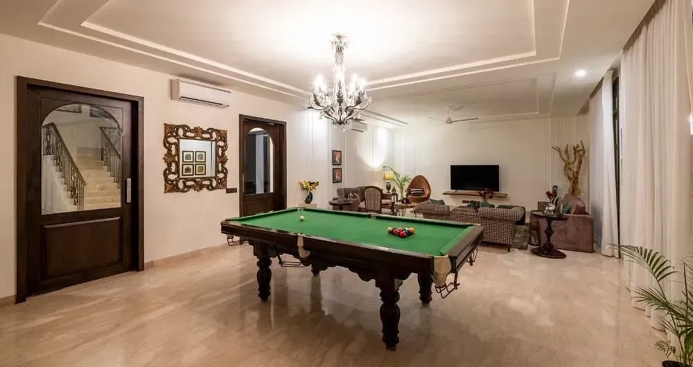 Room with a pool table, chandeliers, wall mirrors, and neutral-coloured decor at Karma Chalets.